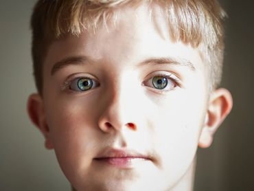 Close-up of a young boy with striking blue-green eyes and blonde hair.
