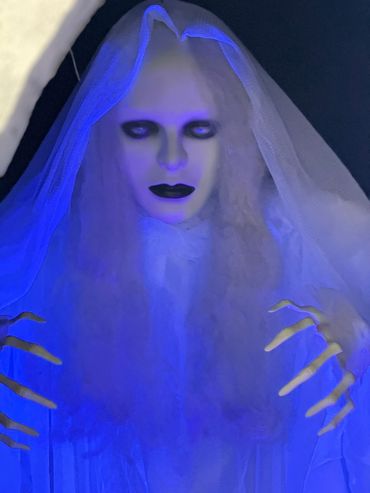 A ghostly figure with pale face and long fingers under blue light.