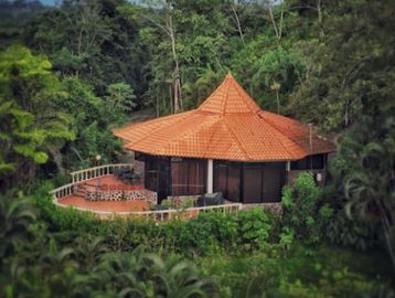 A quaint round house with a tiled roof nestled in lush greenery.