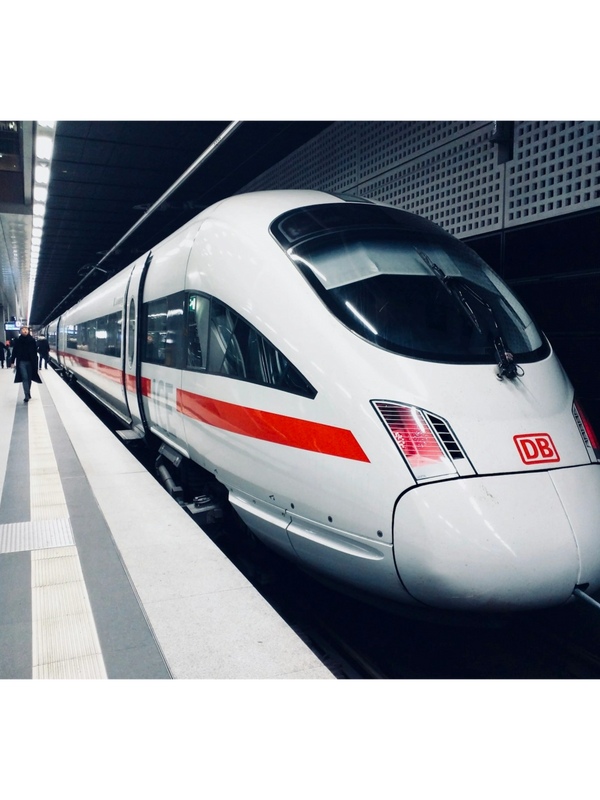 A sleek white and red high-speed train at a modern station platform.