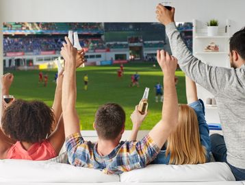 Friends watching football on projector screen at home