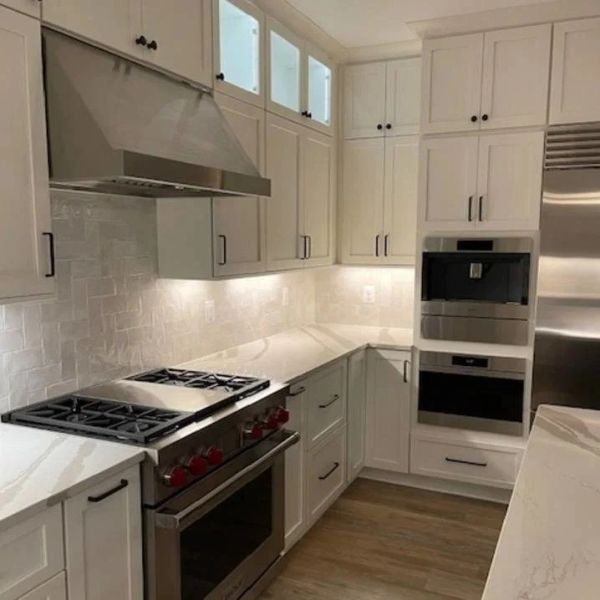 Modern white kitchen with stainless steel appliances.