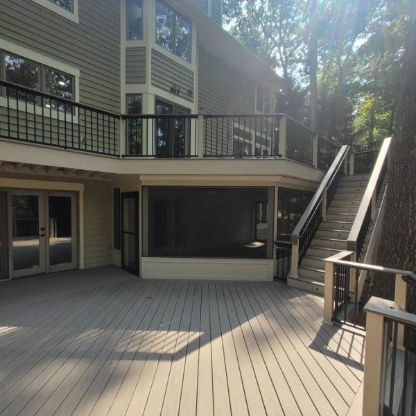 Spacious outdoor deck with stairs and railing attached to a house.