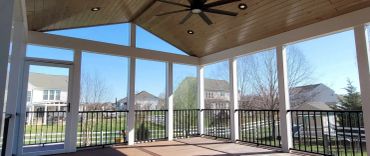 Covered porch with black railing and ceiling fan.