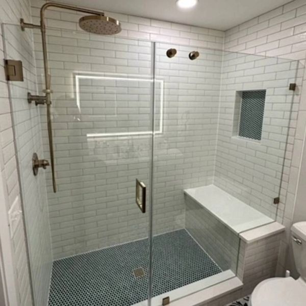 Modern shower with glass door and built-in bench.