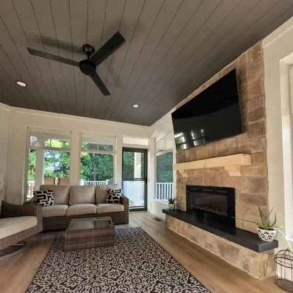 Cozy living room with stone fireplace and ceiling fan.