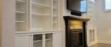 Empty white built-in shelves around a black fireplace.