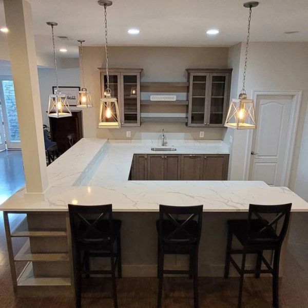 Modern kitchen with marble countertops and pendant lights.