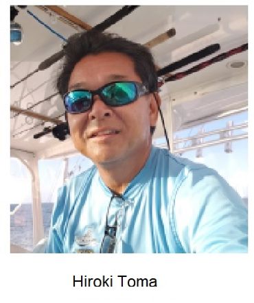 Man wearing sunglasses and a light blue shirt on a boat.