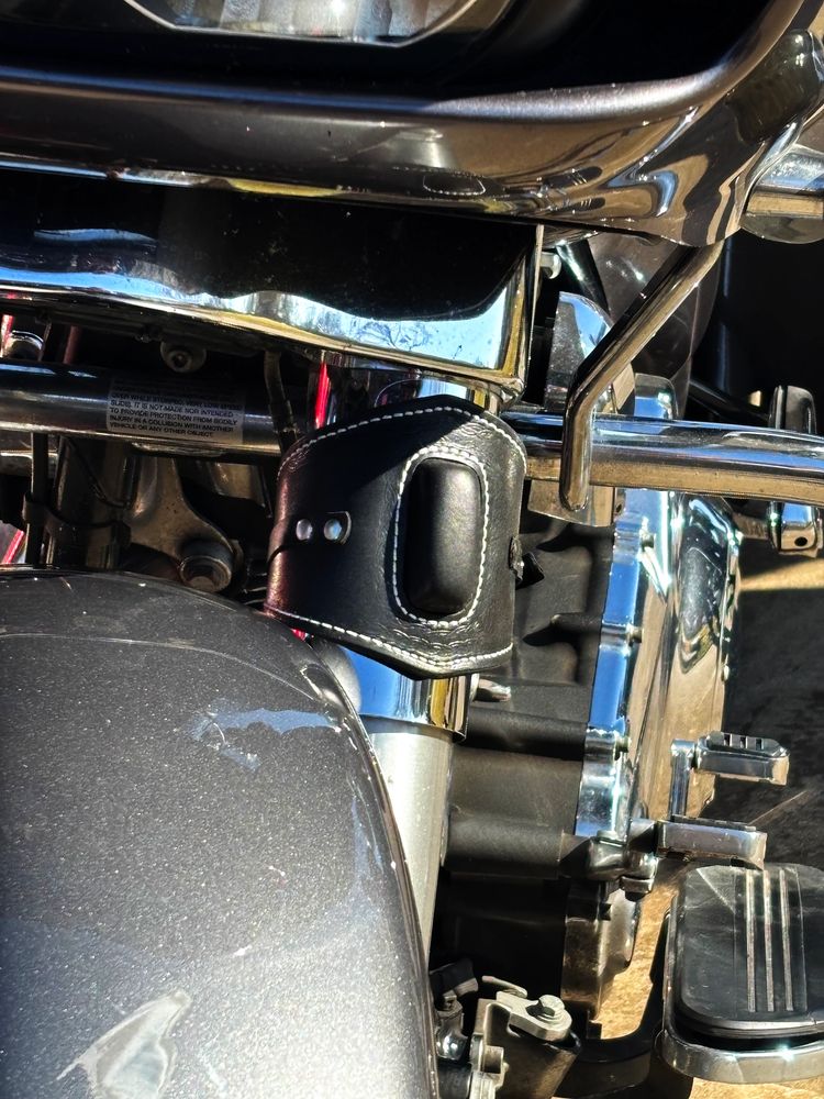 Motorcycle engine with black leather cup holder and chrome details.