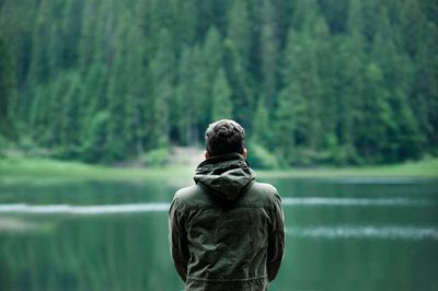 Man standing in calming nature scene overlooking a lake.