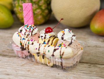 Banana split with whipped cream, chocolate drizzle, and a cherry on top.