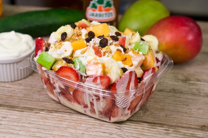 Fresh fruit salad with yogurt and granola in a clear container.