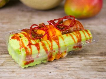 Chopped cucumber and fruit with chili sauce and tamarind candy in a clear plastic container.