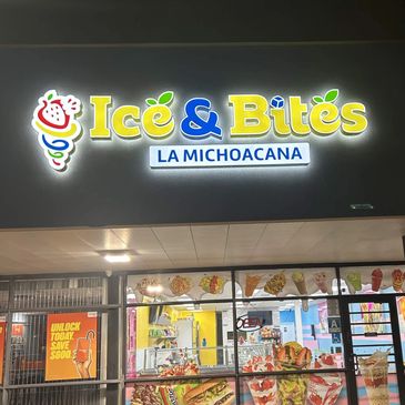 Brightly lit Ice &amp; Bites La Michoacana storefront at night.