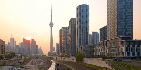Sunset view of Toronto skyline with CN Tower and train tracks.