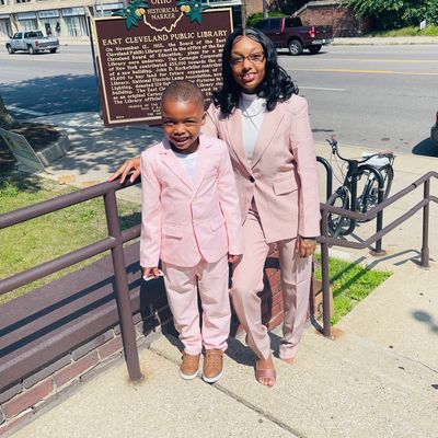A woman and a boy in matching pink suits smile by an Ohio historical marker on a sunny day.