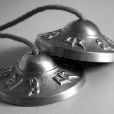 Close-up of traditional Tibetan tingsha cymbals with engraved symbols.