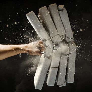 A fist shattering concrete blocks in midair.