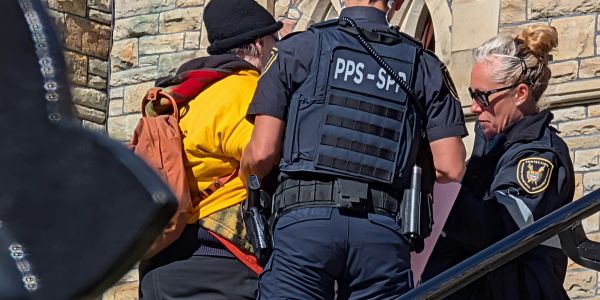Police officers detain a person outside a building.