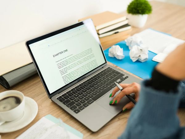 Lady sitting down to a cup of coffee and a laptop.