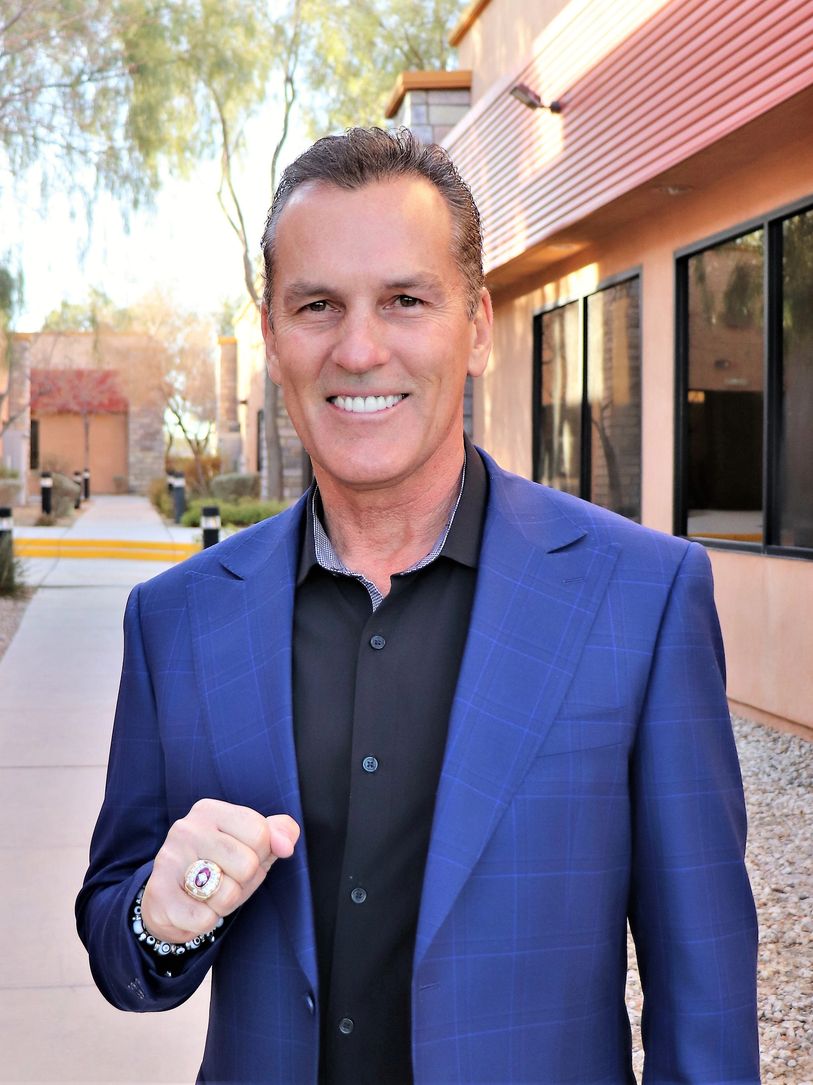 Man in blue suit showing a ring and smiling.