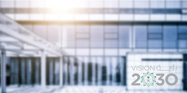 Blurred modern building with Vision 2030 logo in the foreground.