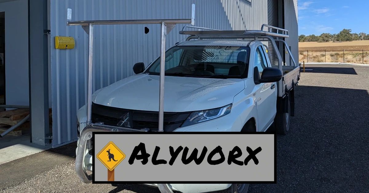 White utility truck with Alyworx logo parked by a metal building.