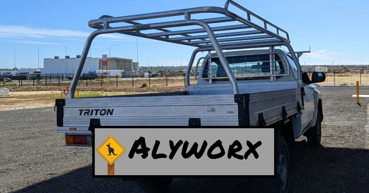 Silver Triton utility truck with a sturdy Alyworx rack on a clear day.