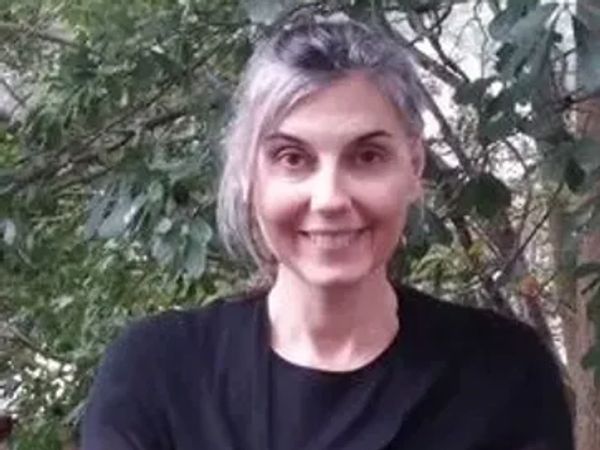Smiling woman with gray hair standing outdoors.