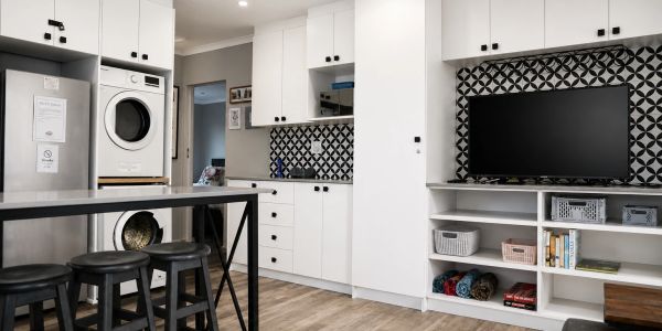 Modern kitchen with white cabinetry and black-patterned backsplash.