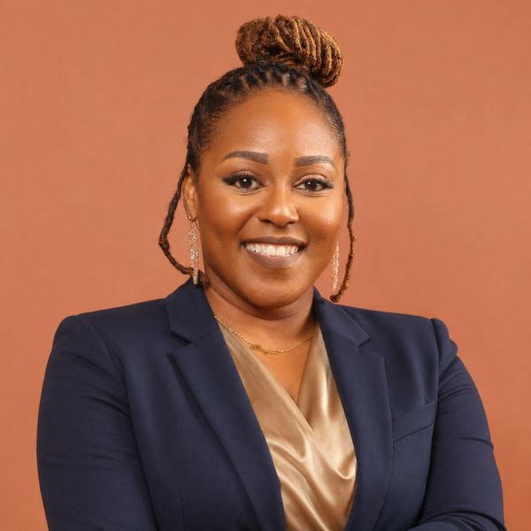 Woman with braided hair in a professional outfit smiling.