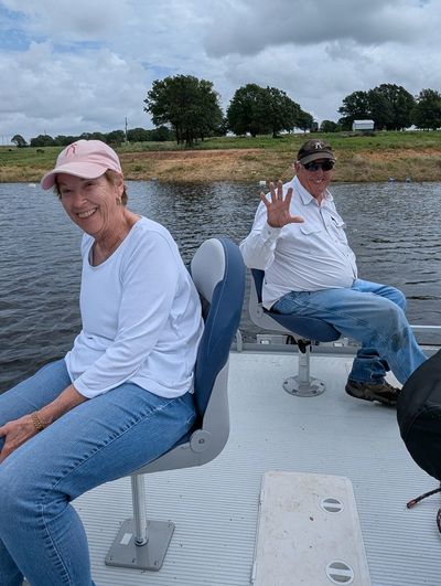 Two people enjoying a boat ride on a calm lake under a cloudy sky.