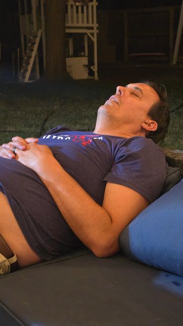 Man sleeping on outdoor couch at night.