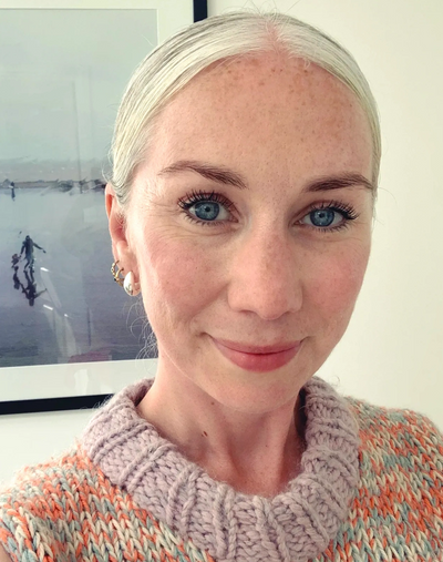 Smiling woman with bright blue eyes and knitted sweater.