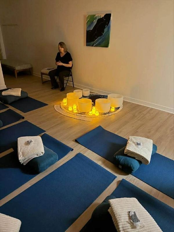 A calm meditation room with mats, cushions, blankets, and glowing candles.