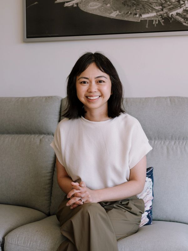Smiling woman sitting on a gray couch.