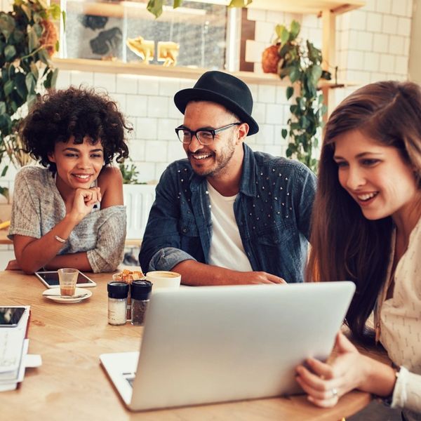 Three friends happily looking at a laptop screen together.