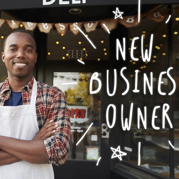 Smiling new business owner in apron stands confidently outside shop.
