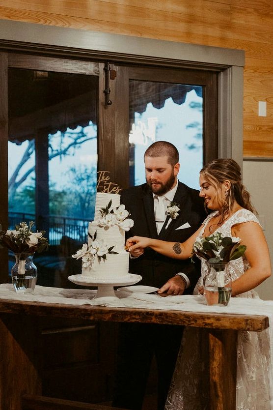 Bride and groom cutting wedding cake indoors.