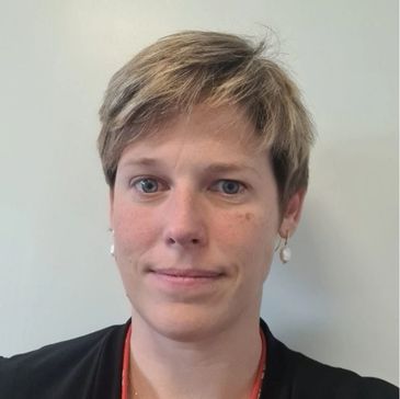 Portrait of a woman with short blonde hair and pearl earrings.
