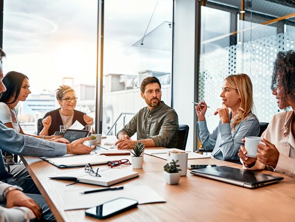 Multinational professionals business people discussing daily topics by table in modern office.