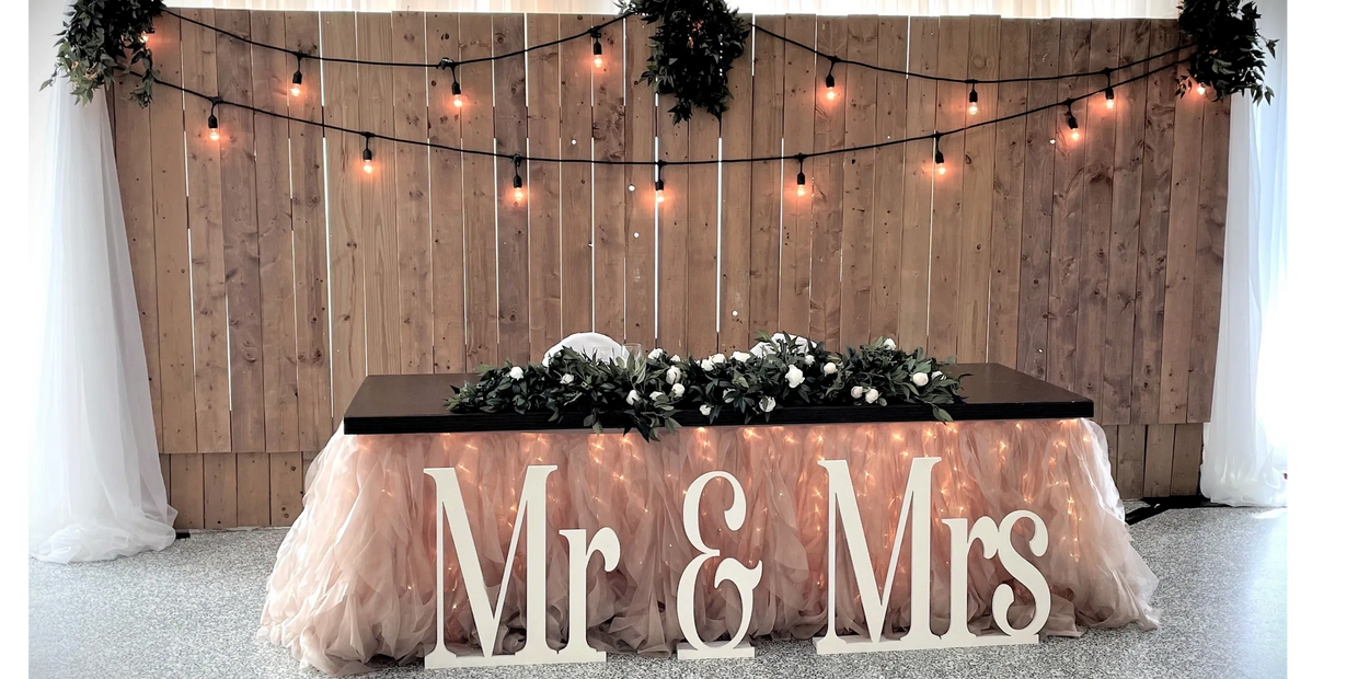 Wooden backdrop and head table with Edison lights