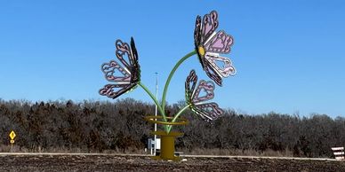 Large butterfly sculptures installed in an outdoor public space under clear blue sky.