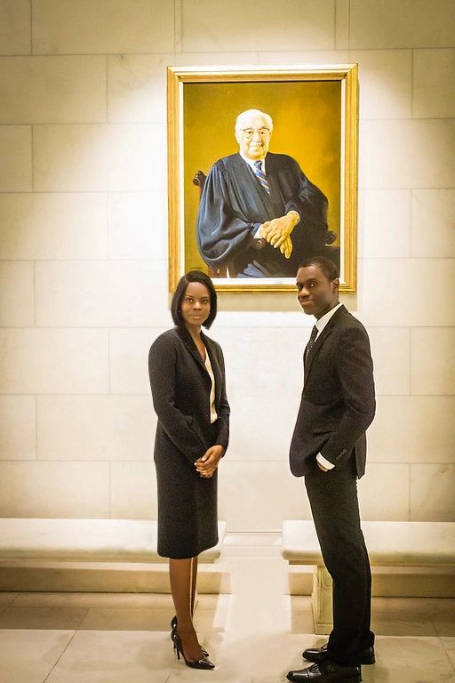 Attorney Theresa Owusu and Attorney Jason Grant standing in front of photo of Justice Marshall.