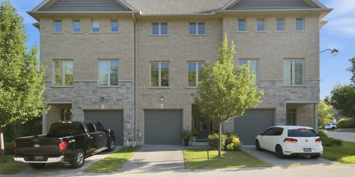A townhouse with three garages and two cars parked outside.