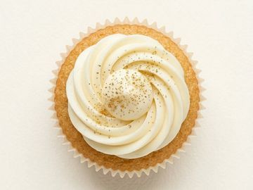 A cupcake with white swirled frosting and gold sprinkles.