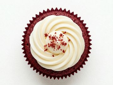 Red velvet cupcake with creamy white frosting and red sprinkles.