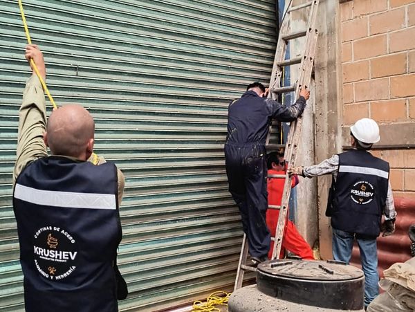 Desmontaje de cortina metálica industrial con herramientas y equipo profesional.