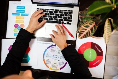 Person working on a laptop surrounded by marketing charts.